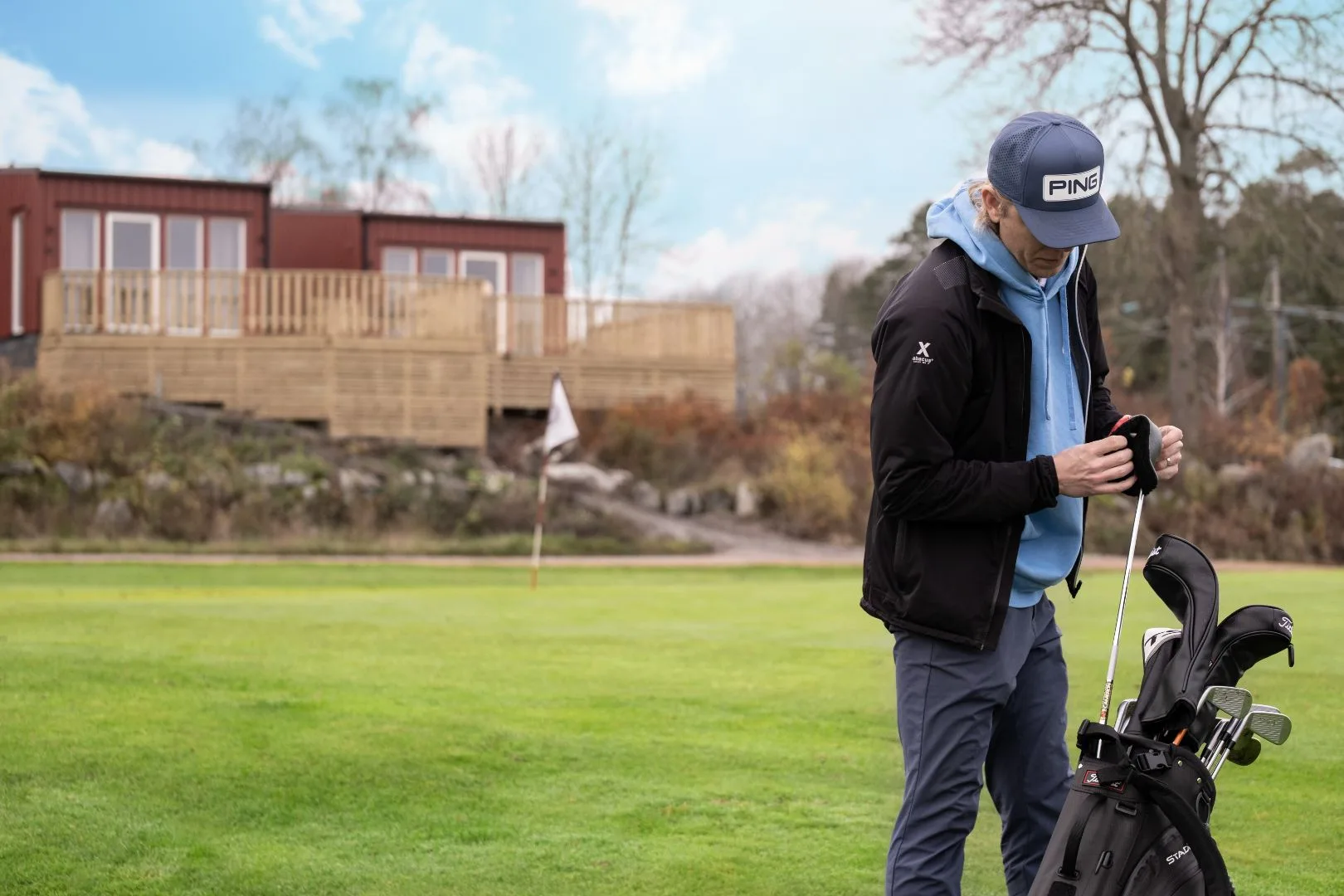 Golfspelare går på banan med mobilahus i bakgrunden