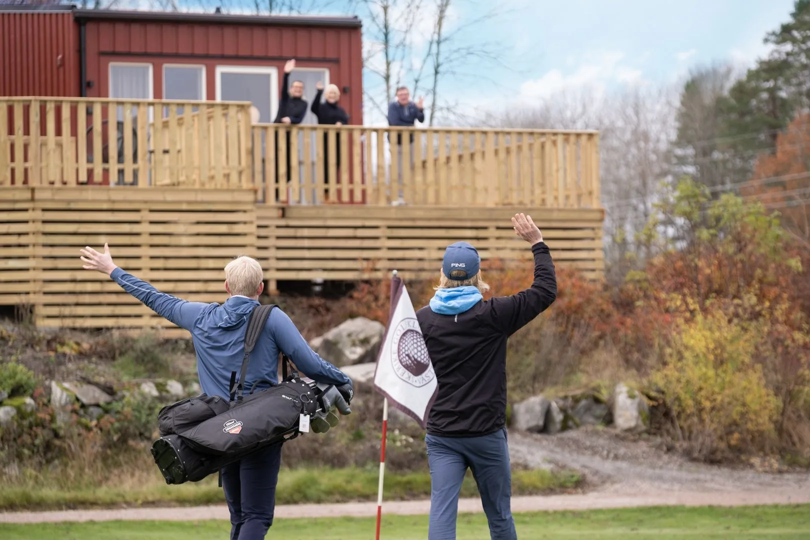 Golfare vinkar vid mobilahus vid golfbana